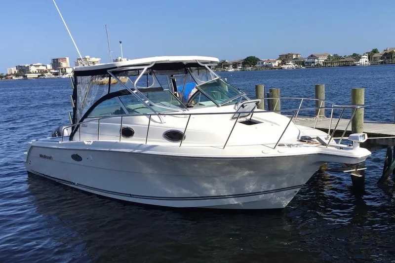The Image of 2001 Wellcraft 290 Coastal boat on trailer, parked outdoors under clear blue sky. - 0