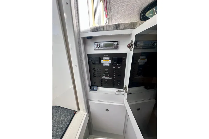 Slide: The Image of Electrical panel inside 2001 Wellcraft 290 Coastal boat, featuring control switches and stereo system. - 16