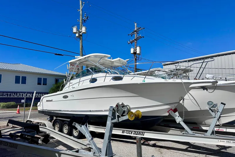 Slide: The Image of 2001 Wellcraft 290 Coastal boat docked by the ocean under a cloudy sky. - 2