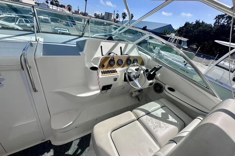 Slide: The Image of 2001 Wellcraft 290 Coastal boat cockpit with steering wheel and seating under sunny skies. - 28