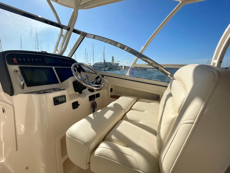 Slide: The Image of 2017 Grady-White 307 Freedom boat interior with helm and seating, sunny marina view. - 22