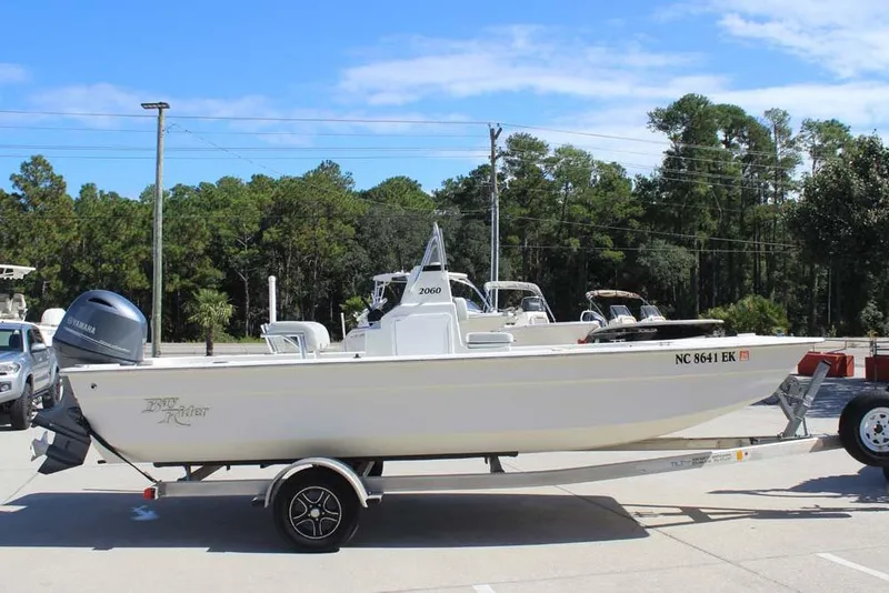 Slide: The Image of 2019 Bay Rider 2060 Skiff on trailer, parked outdoors with trees in background. - 7