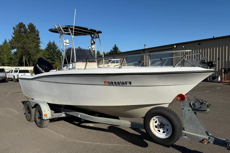 The Image of 1990 Larson DC-204 boat on trailer, parked outdoors under clear blue sky. - 1