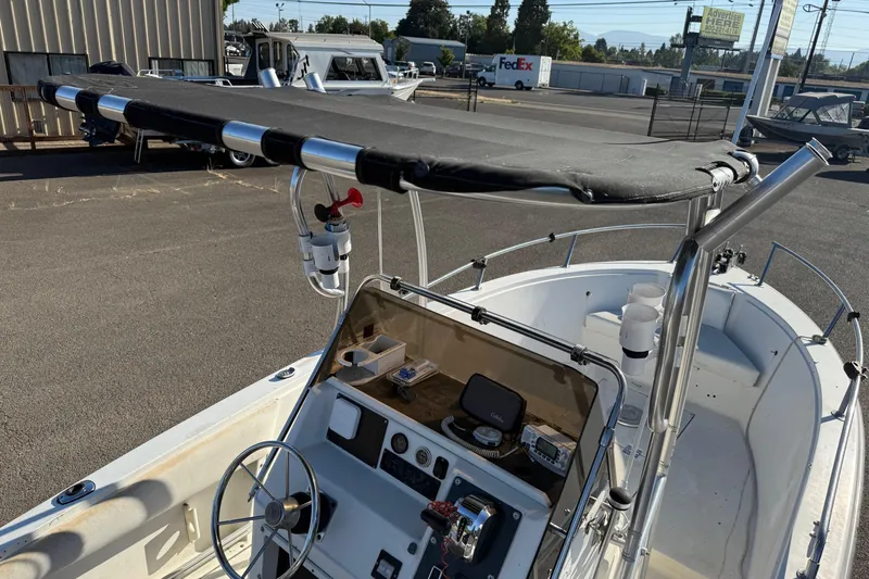 Slide: The Image of 1990 Larson DC-204 boat with canopy, steering wheel, and control panel in a parking lot. - 14