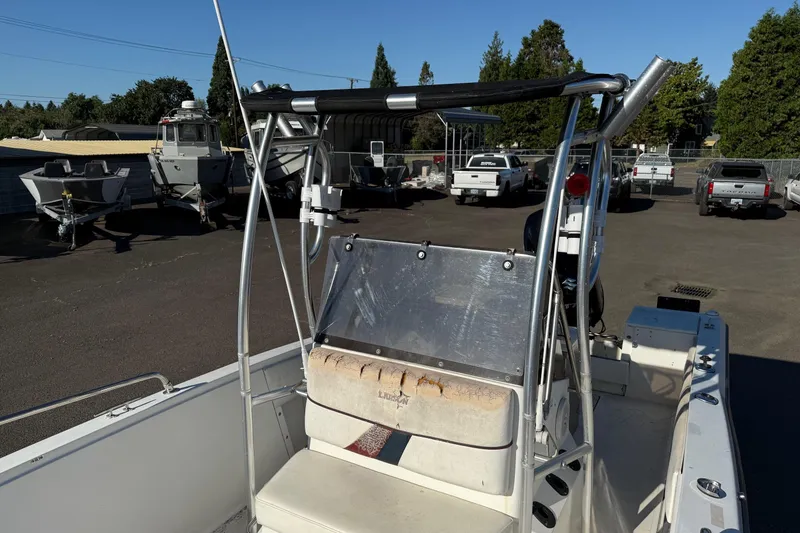 Slide: The Image of 1990 Larson DC-204 boat with seating and metal frame, parked in a lot with other boats. - 16