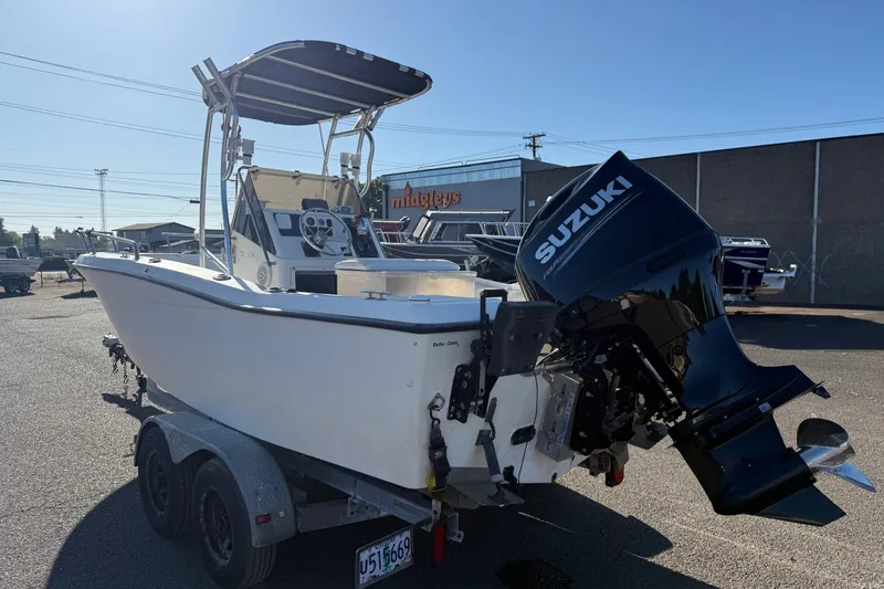 Slide: The Image of 1990 Larson DC-204 boat on trailer with Suzuki outboard motor in parking lot. - 4