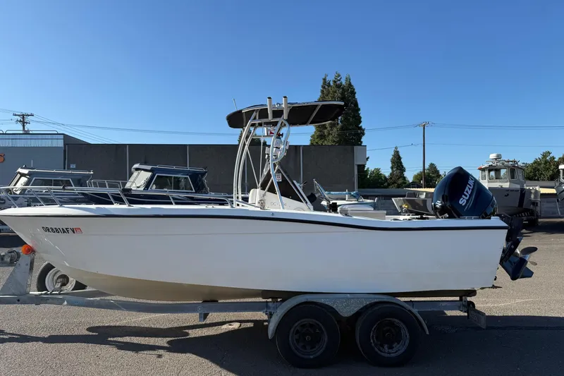 Slide: The Image of 1990 Larson DC-204 boat on trailer with Suzuki outboard motor, parked outdoors. - 5