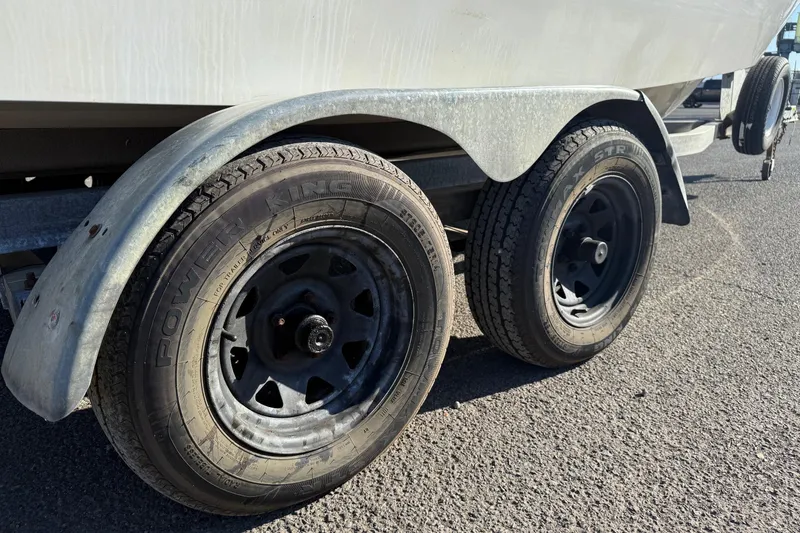 Slide: The Image of Trailer wheels of a 1990 Larson DC-204 boat on asphalt surface. - 8