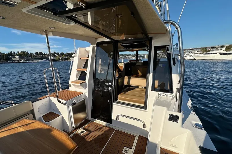 Slide: The Image of 2025 Ranger Tugs R-29 CB boat interior with wood accents and seating, docked on a sunny day. - 10