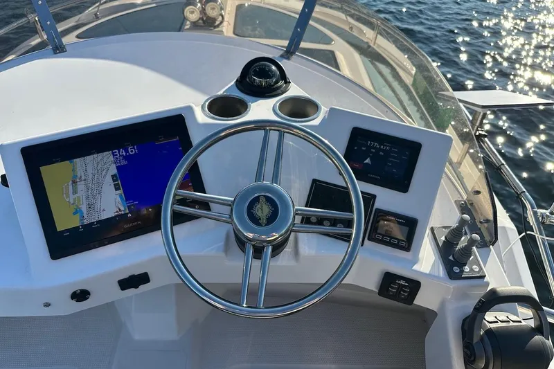 Slide: The Image of 2025 Ranger Tugs R-29 CB helm with navigation screens and steering wheel on open water. - 20