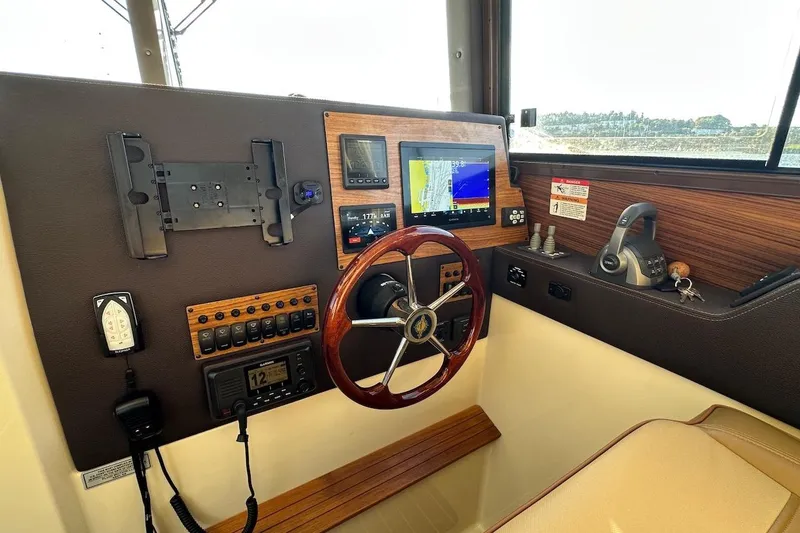 Slide: The Image of 2025 Ranger Tugs R-29 CB helm with navigation controls and wooden steering wheel. - 28
