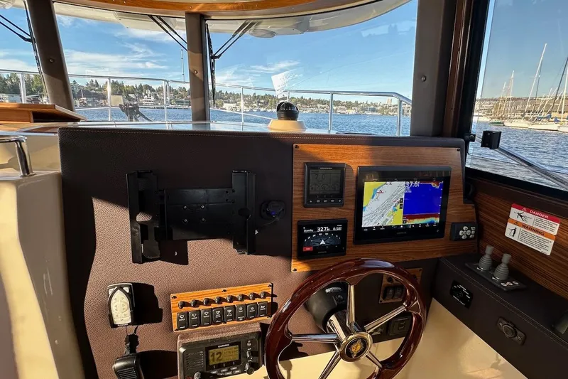 Slide: The Image of 2025 Ranger Tugs R-29 CB helm with navigation screens and steering wheel, overlooking marina. - 29