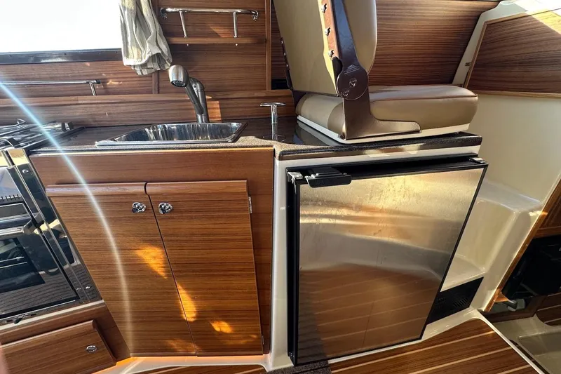 Slide: The Image of 2025 Ranger Tugs R-29 CB interior with wood finish, sink, and stainless steel fridge. - 33