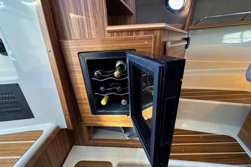 Slide: The Image of 2025 Ranger Tugs R-29 CB interior with open wine cooler, showcasing elegant wood finish. - 35