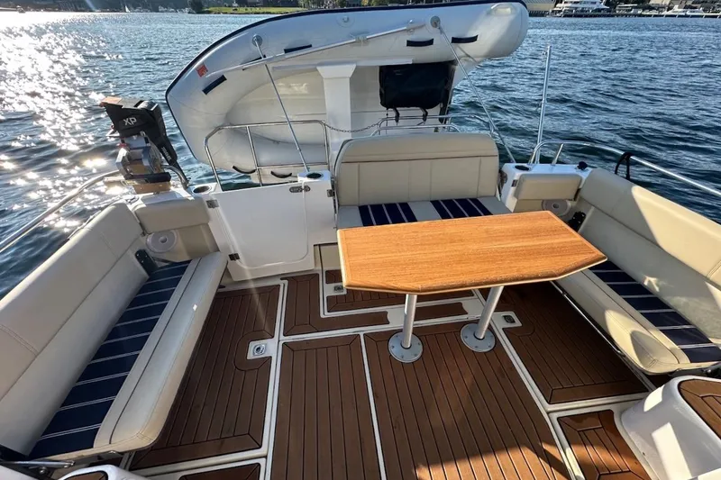 Slide: The Image of 2025 Ranger Tugs R-29 CB boat interior with seating and wooden table on water. - 9