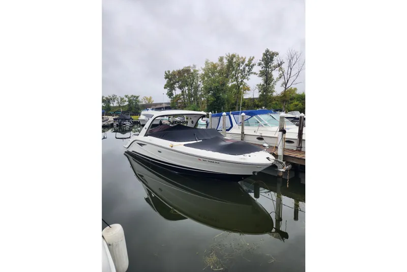 Slide: The Image of 2023 Sea Ray SLX 310 boat docked in a marina, surrounded by trees and calm water. - 36