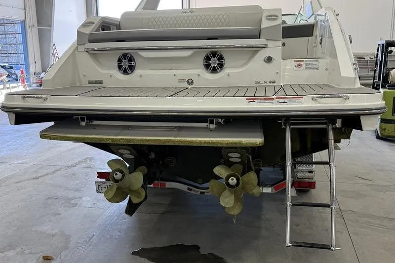 Slide: The Image of 2023 Sea Ray SLX 310 boat rear view with propellers and swim platform in a warehouse. - 6