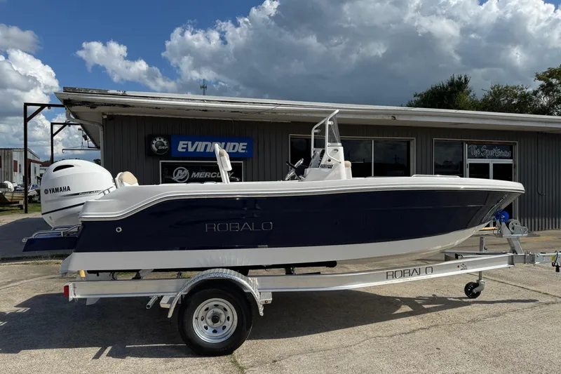 Slide: The Image of 2026 Robalo R160 Center Console boat on trailer, parked outside dealership. - 3