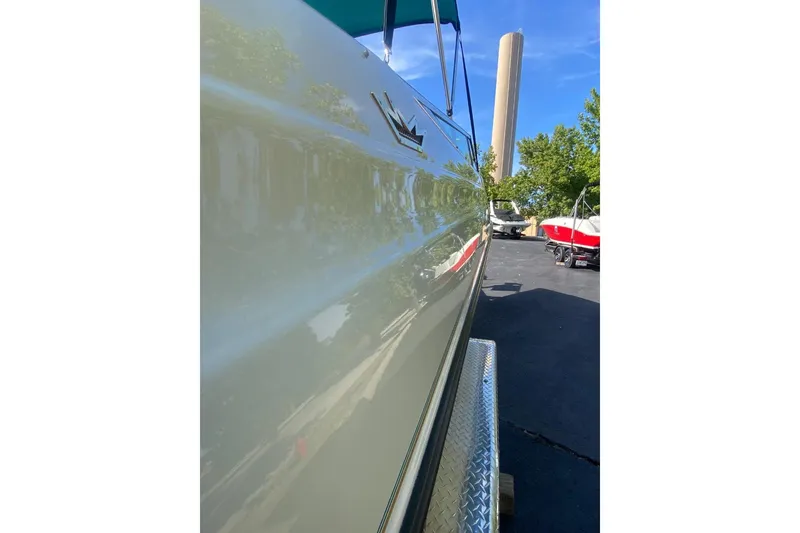 Slide: The Image of 1996 Crownline 266 BR boat side view with shiny finish, parked outdoors. - 10