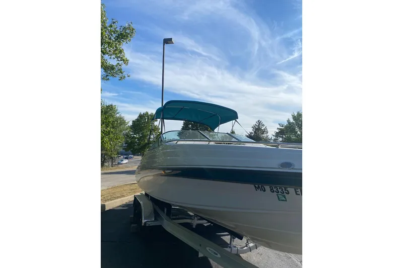 Slide: The Image of 1996 Crownline 266 BR boat on trailer with blue canopy under clear sky. - 11
