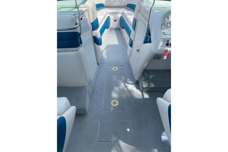 Slide: The Image of 1996 Crownline 266 BR boat interior with blue and white seating, clean carpeted floor. - 3