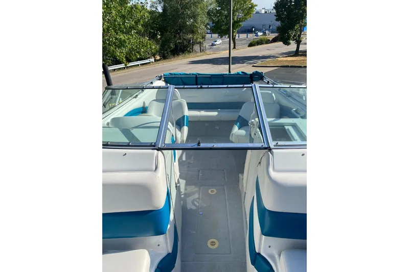 Slide: The Image of 1996 Crownline 266 BR boat interior with blue and white seating, docked outdoors. - 8