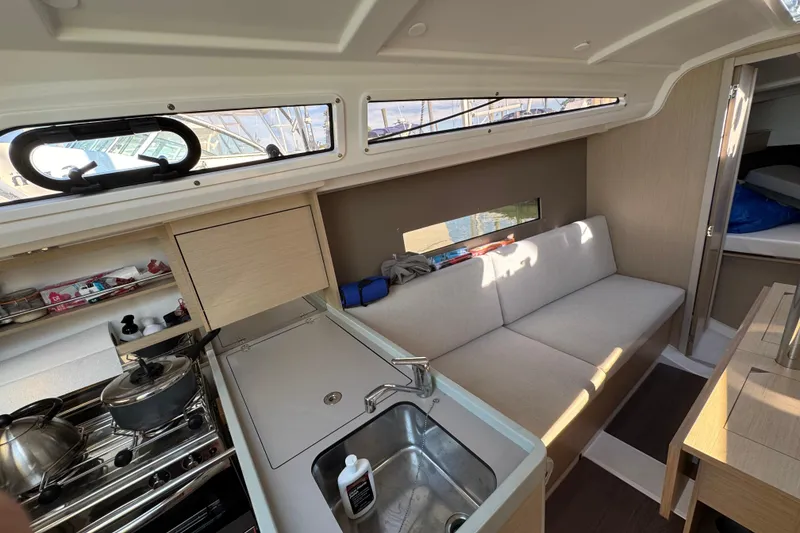 Slide: The Image of Interior of 2020 Beneteau Oceanis 30.1 yacht, featuring a compact kitchen and cozy seating area. - 24