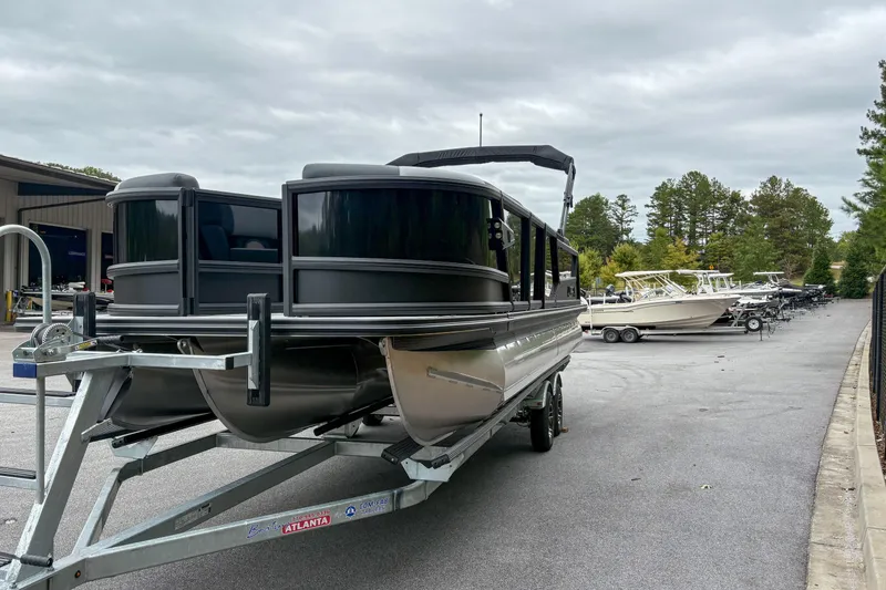 Slide: The Image of 2026 Alera M23Q pontoon boat on trailer in marina parking lot. - 3