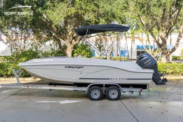 Slide: The Image of 2021 Starcraft SVX 191 OB boat on trailer, parked outdoors with trees in background. - 1