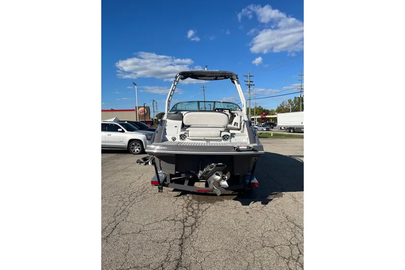 Slide: The Image of 2026 Crownline Eclipse E235 boat, rear view, parked on pavement under a clear blue sky. - 1