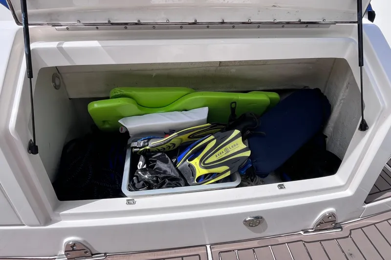 Slide: The Image of Open storage compartment on 2020 Sea Ray Sundancer 320 Outboard with snorkeling gear and accessories. - 12