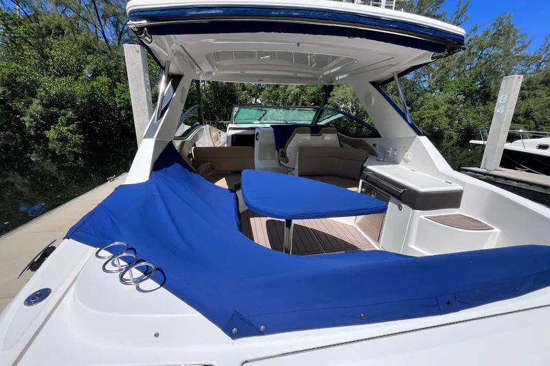 Slide: The Image of 2020 Sea Ray Sundancer 320 Outboard with blue cover, docked in a lush, green marina. - 3