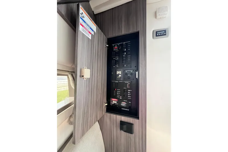 Slide: The Image of Electrical panel inside 2020 Sea Ray Sundancer 320 Outboard boat, with open cabinet door. - 59