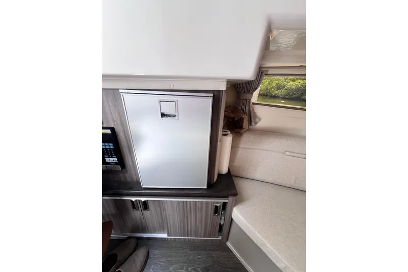 Slide: The Image of 2020 Sea Ray Sundancer 320 Outboard interior with compact fridge and seating area. - 60