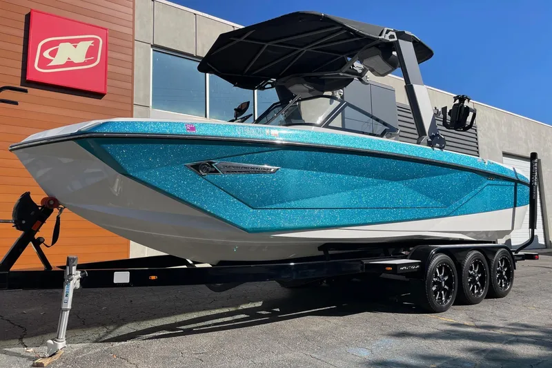 Slide: The Image of 2022 Nautique Super Air Nautique G25 boat with sparkling blue finish on a trailer. - 2