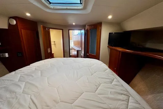 Slide: The Image of 2001 Silverton 42 Convertible yacht bedroom with skylight, TV, and wooden cabinetry. - 12