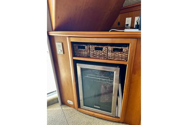 Slide: The Image of Wooden cabinet with mini fridge and wicker baskets on a 2001 Silverton 42 Convertible yacht. - 22