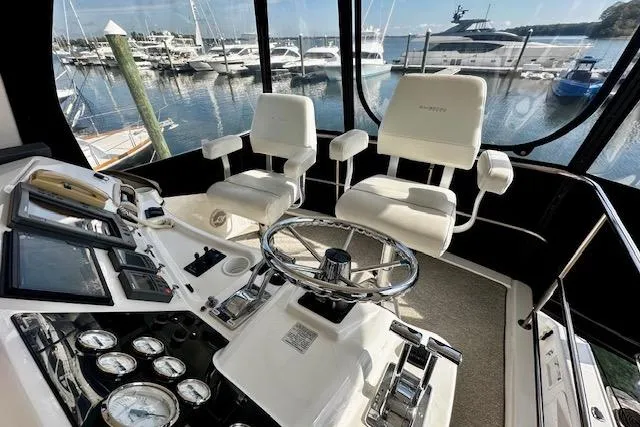 Slide: The Image of 2001 Silverton 42 Convertible yacht cockpit with steering wheel, gauges, and marina view. - 29