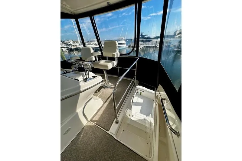 Slide: The Image of 2001 Silverton 42 Convertible yacht interior with helm chairs and marina view. - 30