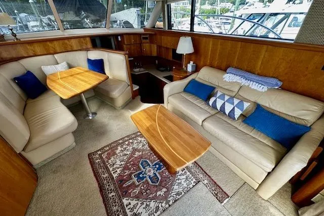 Slide: The Image of 2001 Silverton 42 Convertible yacht interior with beige seating, wooden tables, and decorative pillows. - 4
