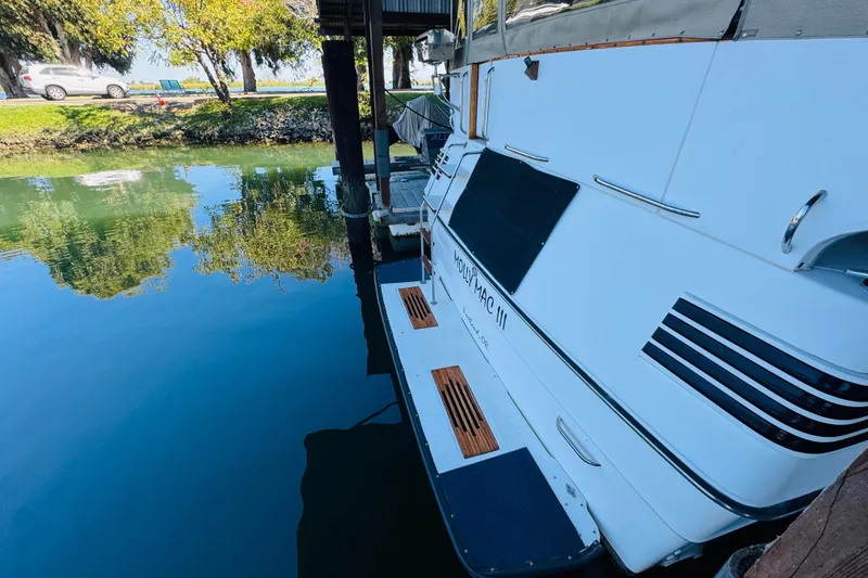 Slide: The Image of 1988 Sea Ray 415 Aft Cabin yacht docked by calm water, reflecting trees. - 11
