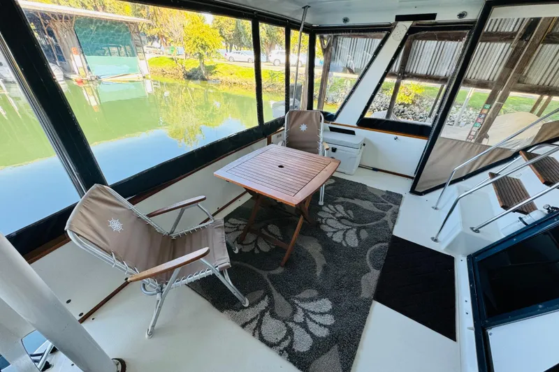 Slide: The Image of 1988 Sea Ray 415 Aft Cabin interior with chairs, table, and scenic water view. - 13