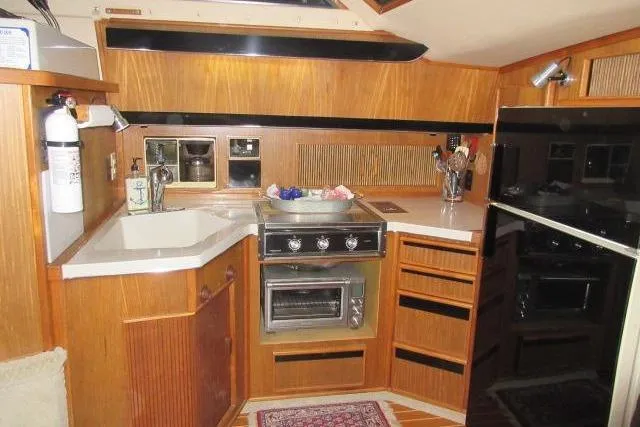 Slide: The Image of 1988 Sea Ray 415 Aft Cabin kitchen with wood cabinetry and modern appliances. - 27