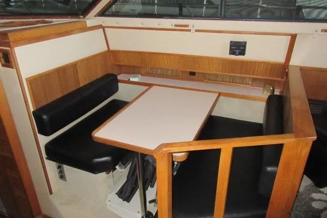 Slide: The Image of 1988 Sea Ray 415 Aft Cabin interior dining area with wood accents and black seating. - 29