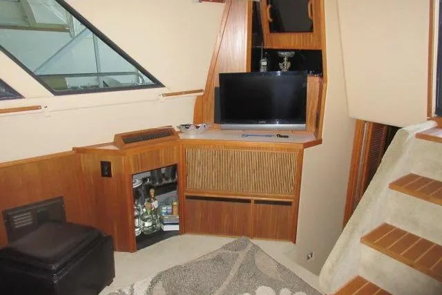 Slide: The Image of 1988 Sea Ray 415 Aft Cabin interior with TV, wooden cabinetry, and stairs. - 30
