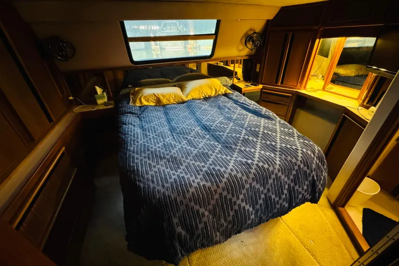 Slide: The Image of Cozy bedroom in 1988 Sea Ray 415 Aft Cabin with blue bedding and wooden cabinetry. - 32