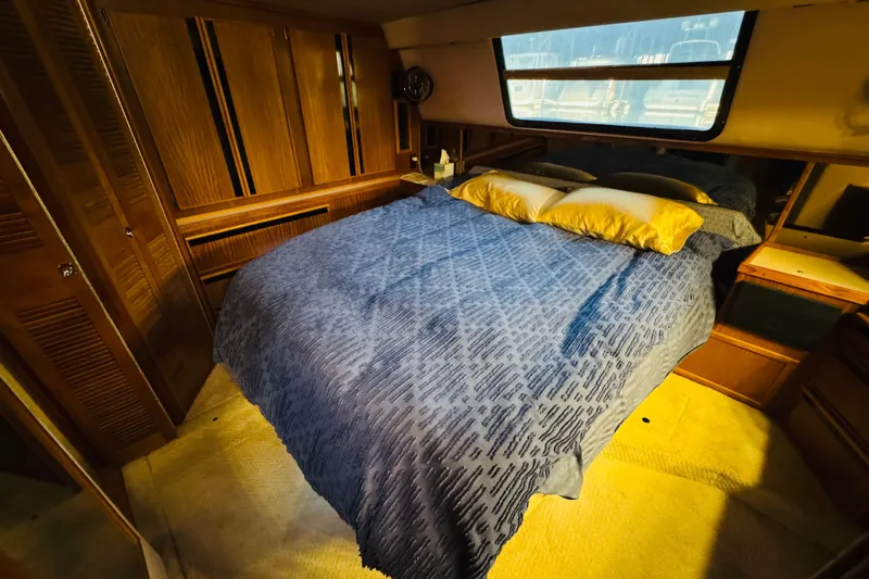 Slide: The Image of Cozy bedroom in 1988 Sea Ray 415 Aft Cabin yacht with blue bedding and wooden cabinetry. - 35