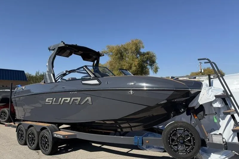 Slide: The Image of 2025 Supra SE 575 boat on trailer under clear blue sky. - 3