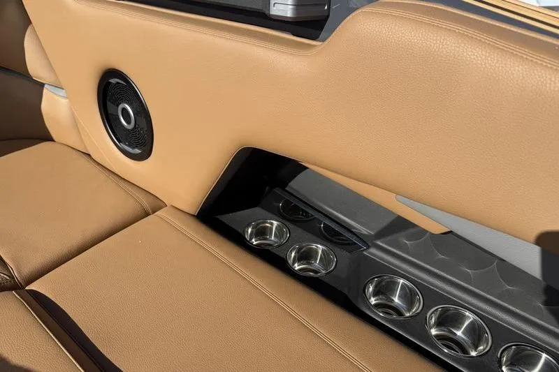 Slide: The Image of 2025 Supra SE 575 interior with tan leather seats and built-in cup holders. - 7