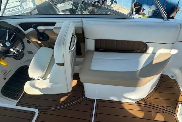 Slide: The Image of 2015 Cobalt 26SD boat interior with white and tan seating, wooden flooring, and steering wheel. - 16
